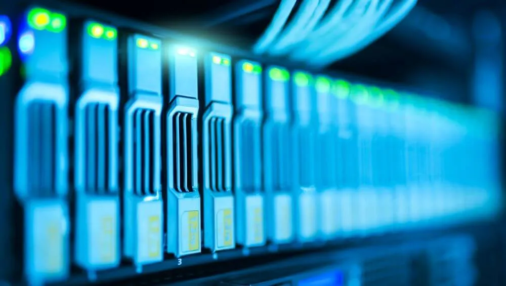 Close-up de conjunto de servidores em rack de data center com luzes LED verdes e cabos de rede azuis conectados.
